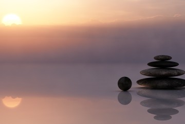 A sunset with a stack of rocks in a reflection